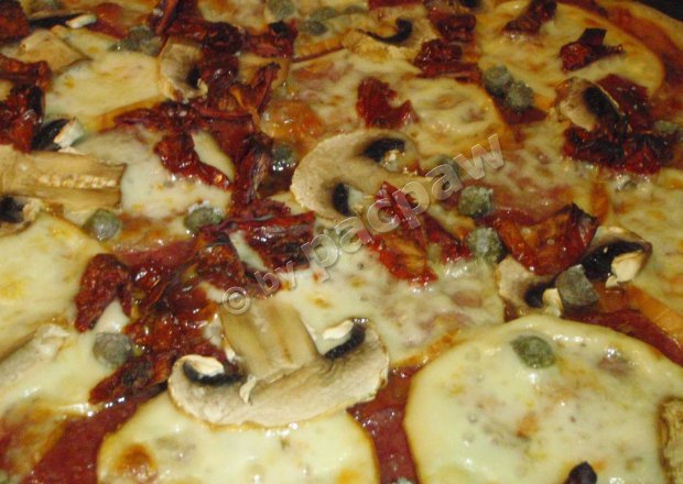 Fotografia przedstawiająca Pizza z mozzarellą wędzoną, salami i kaparami