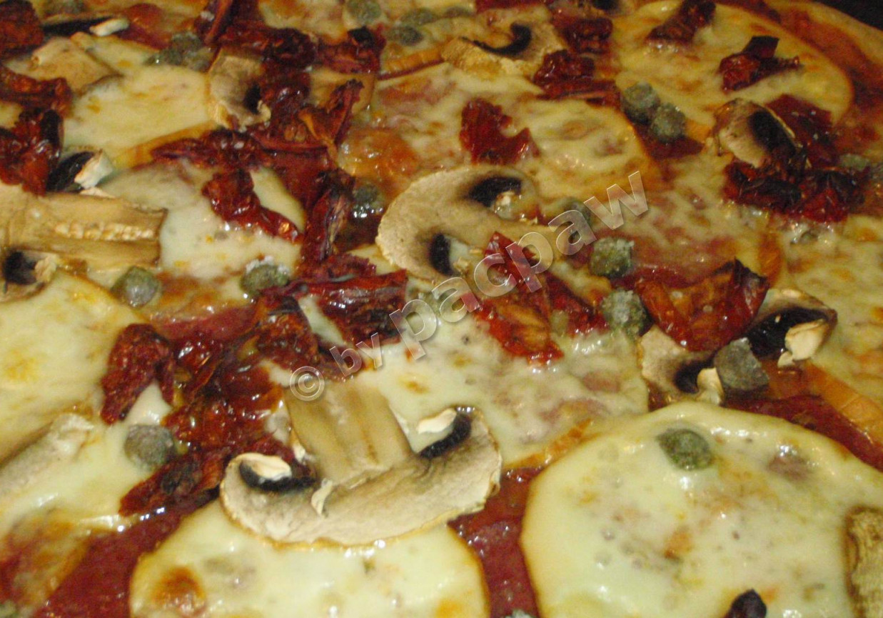 Pizza z mozzarellą wędzoną, salami i kaparami foto
