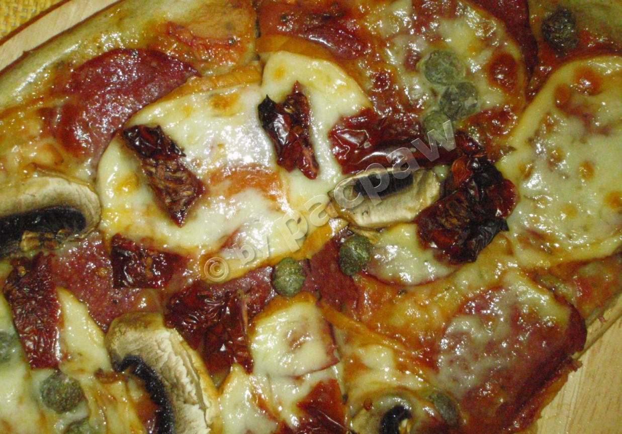 Pizza z mozzarellą wędzoną, salami i kaparami foto