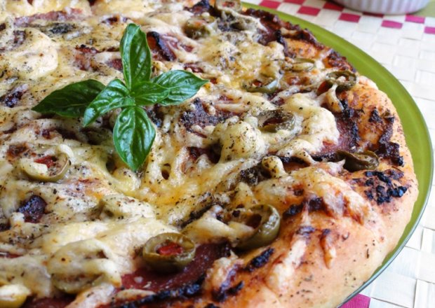 Fotografia przedstawiająca Pizza z pesto, salami i oliwkami