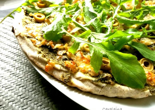 Fotografia przedstawiająca pizza z pesto z rukoli i oliwkami