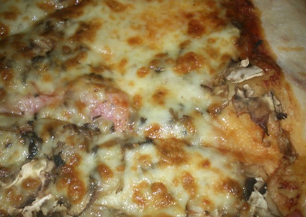 Fotografia przedstawiająca pizza z pieczarkami i szynką na kruchym cieście