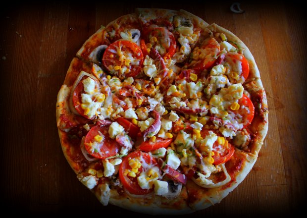 Fotografia przedstawiająca Pizza z pomidorami, fetą i szynką