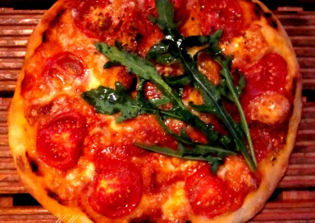 Fotografia przedstawiająca Pizza z pomidorami, mozzarellą i rukolą