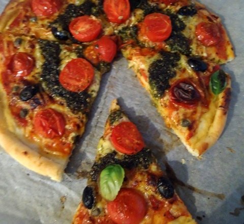 Fotografia przedstawiająca Pizza z pomidorkami, oliwkami i pesto