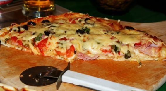 Fotografia przedstawiająca Pizza z szynką mozzarellą i oliwkami