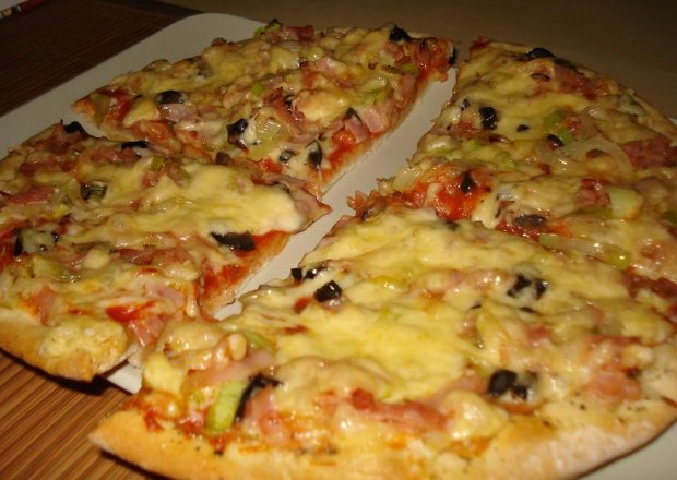 Fotografia przedstawiająca Pizza z szynką parmeńską, porem i czarnymi oliwkami