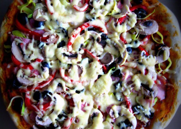 Fotografia przedstawiająca Pizza z szynką, porem, czarnymi oliwkami i papryką