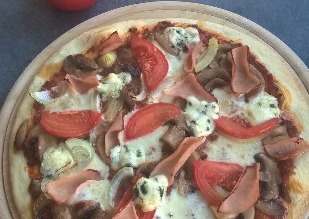 Fotografia przedstawiająca Pizza z szynką, serem, pomidorem i pieczarkami