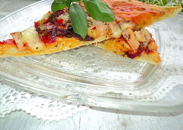 Fotografia przedstawiająca Pizza ziołowa na delikatnym cieście z duszoną cebulką i warzywami