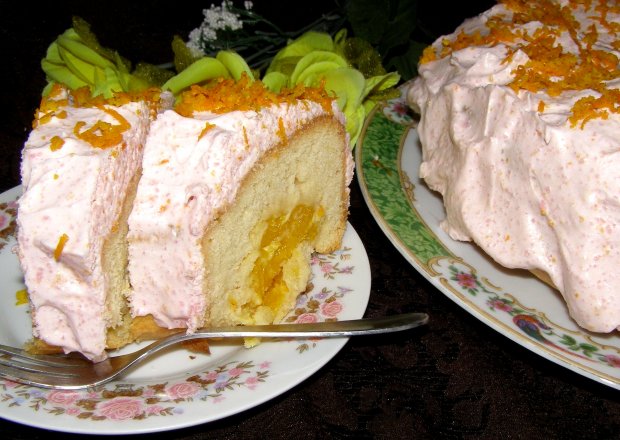 Fotografia przedstawiająca pomarańczowe ciasto z kremem śmietanowym...