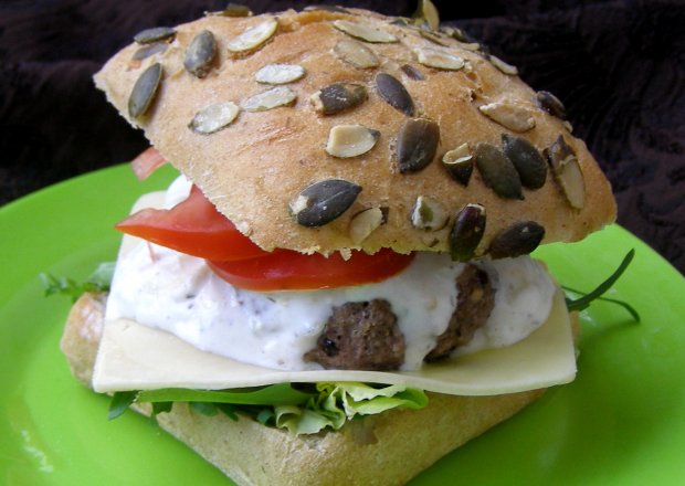 Fotografia przedstawiająca pora na domowego hamburgera z sosem czosnkowym jogurtowym i rukolą w bułce dyniowej...