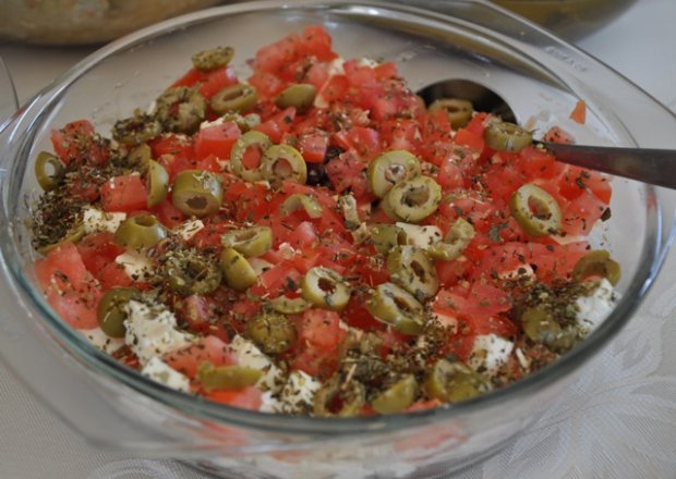 Fotografia przedstawiająca przekładana sałatka z pomidorem cebulą, fasolą i oliwkami