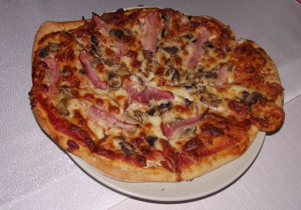 Rumiana pizza z mozzarellą, pieczarkami i boczkiem na ziołowym spodzie foto