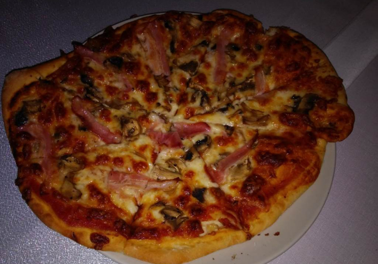Rumiana pizza z mozzarellą, pieczarkami i boczkiem na ziołowym spodzie foto