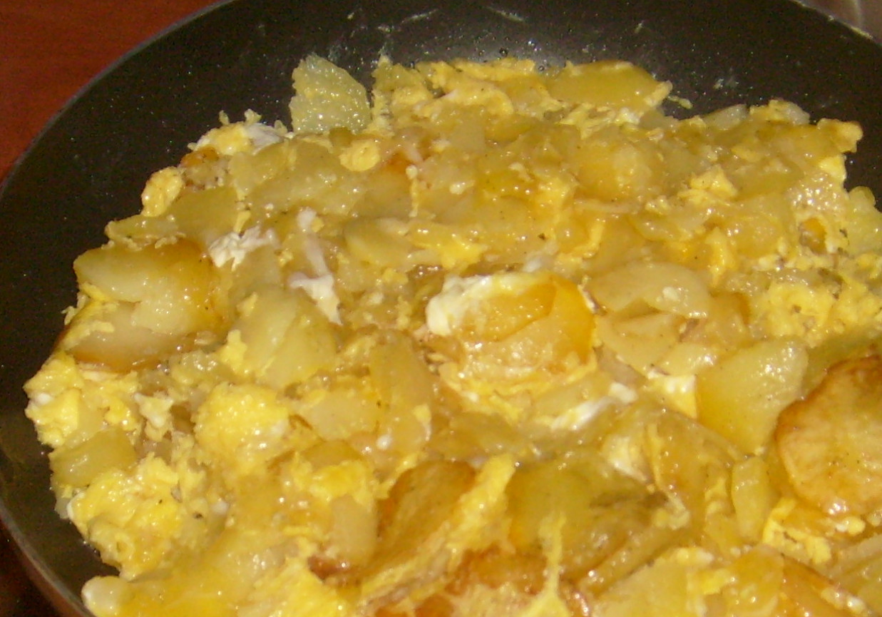 Smażone ziemniaki w plastrach zalewane jajkami foto