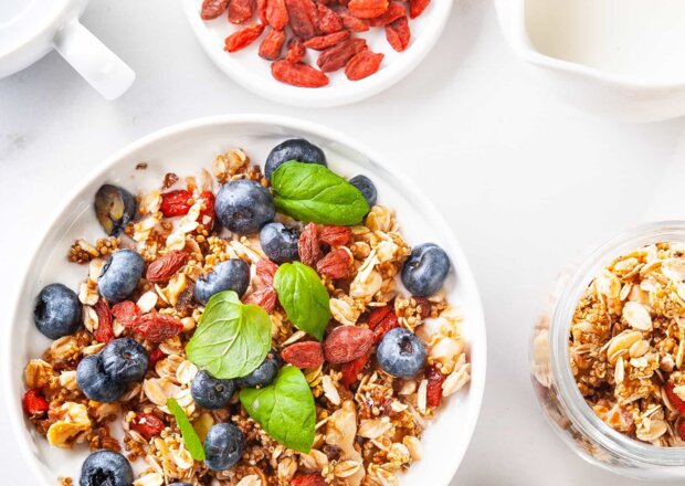 Fotografia przedstawiająca Śniadanie: Granola z komosy ryżowej, płatków owsianych i orzechów z jogurtem, borówkami i jagodam...