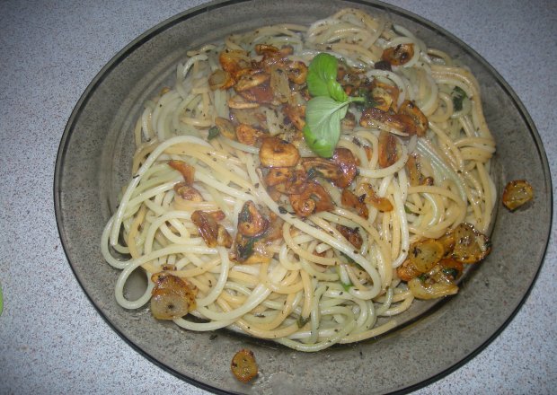 Fotografia przedstawiająca spagetti z płatkami czosnkowmi, bazylią i mozarellą