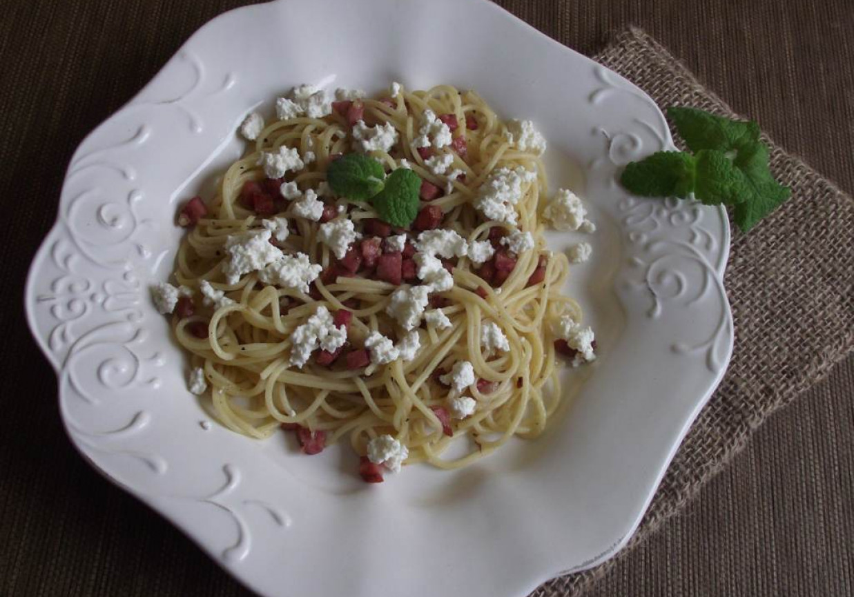 Spaghetti z kiełbasą smażoną z cebulą podane z białym serem foto