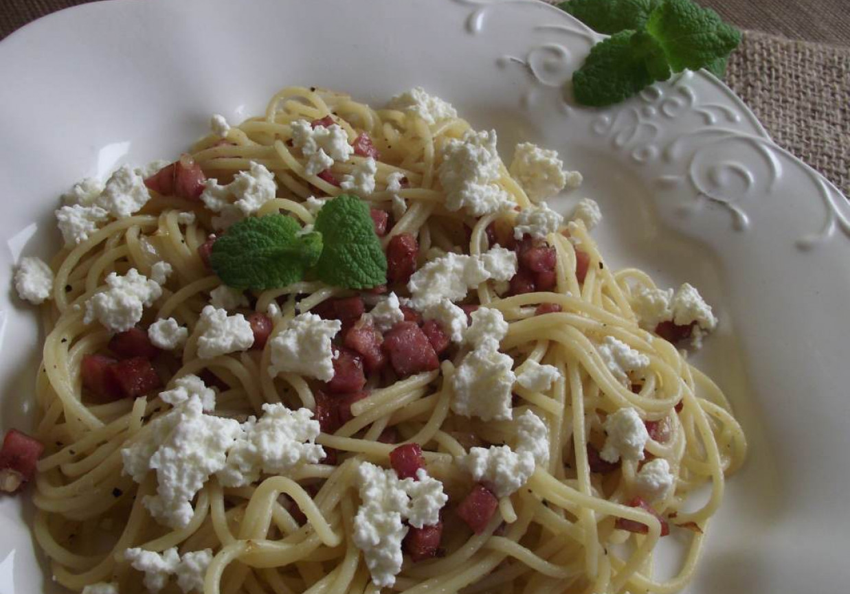 Spaghetti z kiełbasą smażoną z cebulą podane z białym serem foto