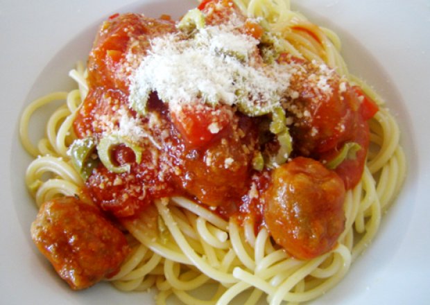 Fotografia przedstawiająca spaghetti z klopsikami w sosie pomidorowym z papryką i oliwkami
