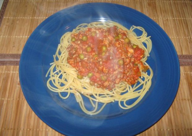 Fotografia przedstawiająca Spaghetti z mięsnym  sosem pomiodorowym i groszkiem