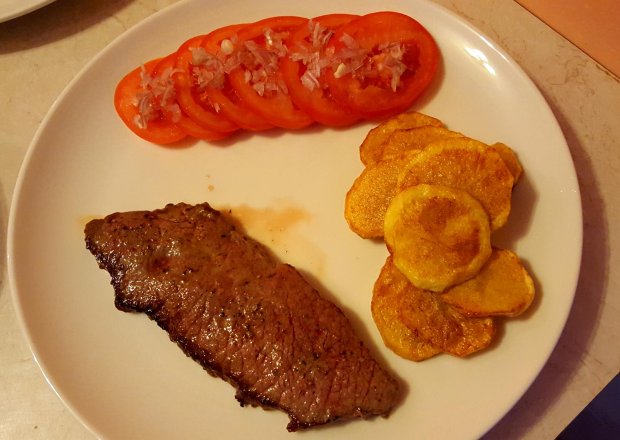 Fotografia przedstawiająca Stek z wołowiny z talarkami i pomidorami