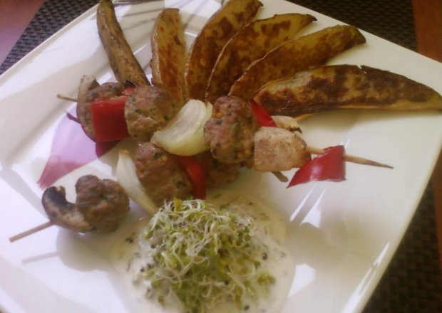 Fotografia przedstawiająca Szaszłyk z kulkami mięsnymi i warzywami z dodatkiem pieczonych ziemniaczków i sosu z kiełków