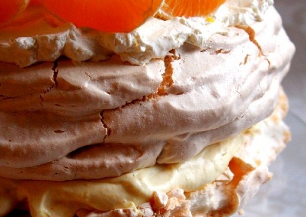 Fotografia przedstawiająca Tort bezowy z kremem pomarańczowym i bitą śmietaną
