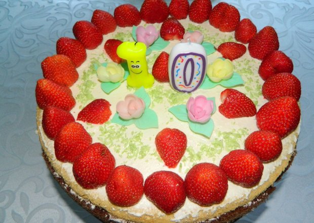 Fotografia przedstawiająca Tort urodzinowy biszkoptowy z kremem, masą śmietanową i truskawkami