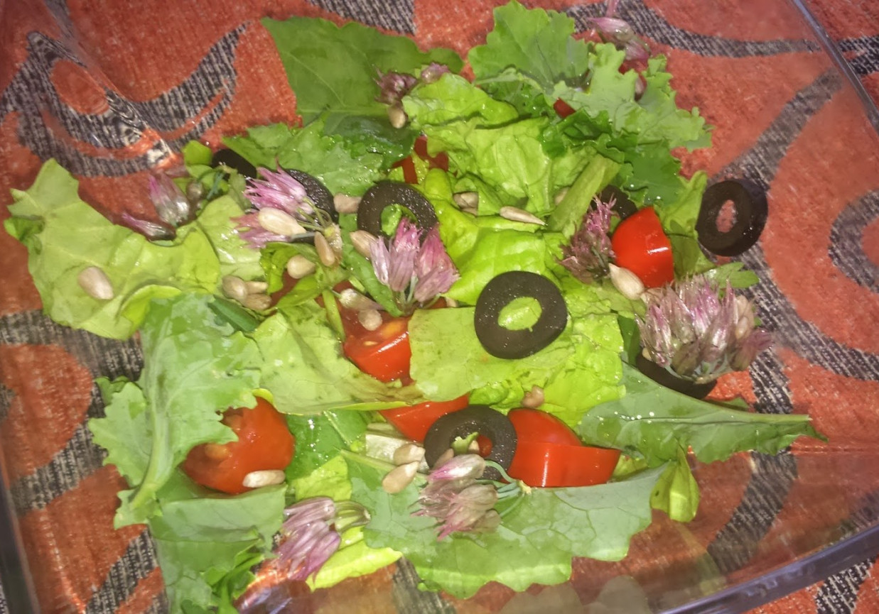 Wiosenna surówka z oliwkami, pomidorkami, słonecznikiem i kwiatem szczypiorku. foto