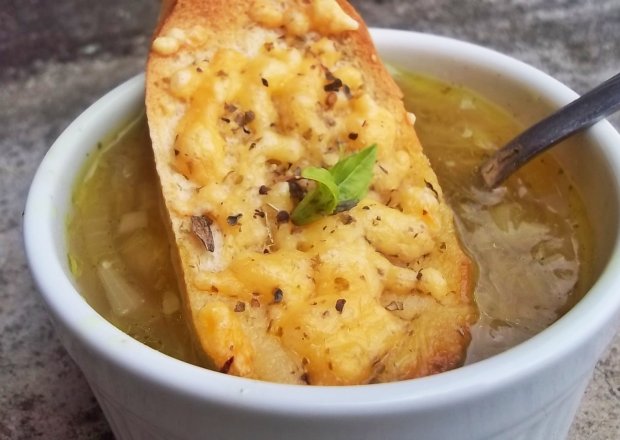 Fotografia przedstawiająca Zupa cebulowa z bagietką i  serem