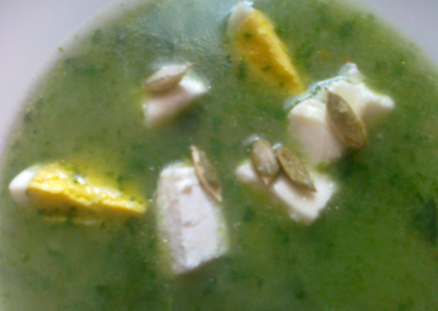 Fotografia przedstawiająca zupa szpinakowa z kostkami białego sera i pestkami dyni