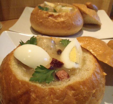 Fotografia przedstawiająca Żurek w chlebie z kiełbasą, jajkiem i ziemniaczkami